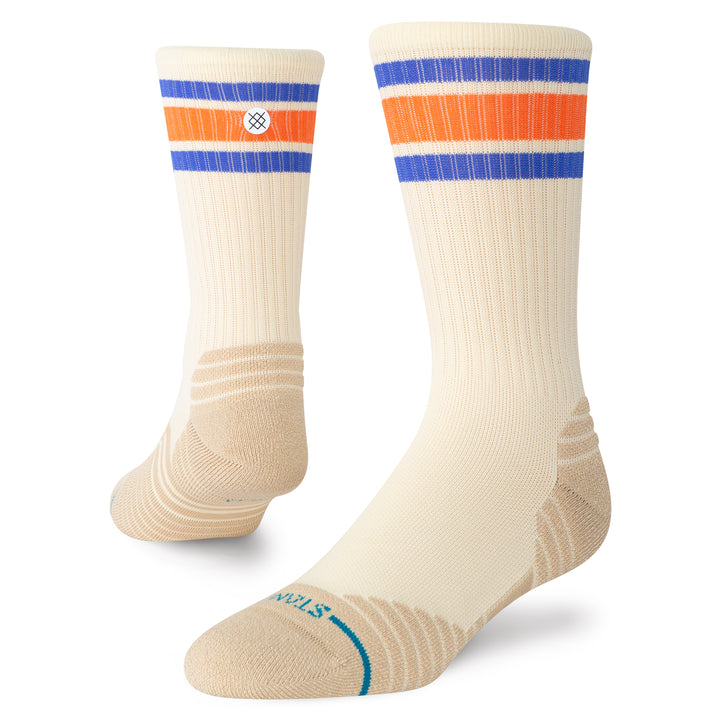 A pair of beige-coloured crew socks with orange and blue stripes at the top and a STANCE circular icon on the rear calf.