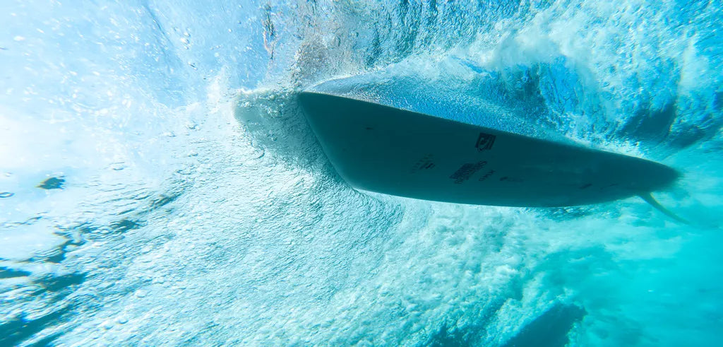 Surfboard cutting through water with a large wave