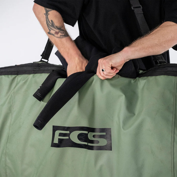 Wetsuit being stored in the stash pocket of the FCS Day-X longboard travel bag in Alpine green.