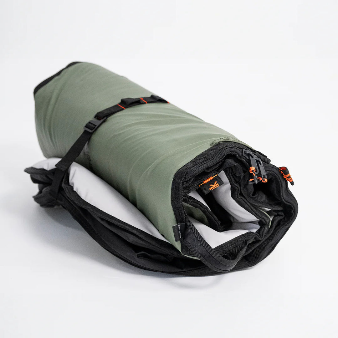 Rolled-up surfboard bag with black straps on a white background
