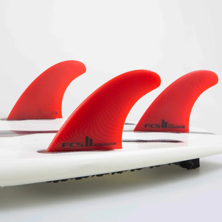 Close-up of a surfboard with red fins on a white background