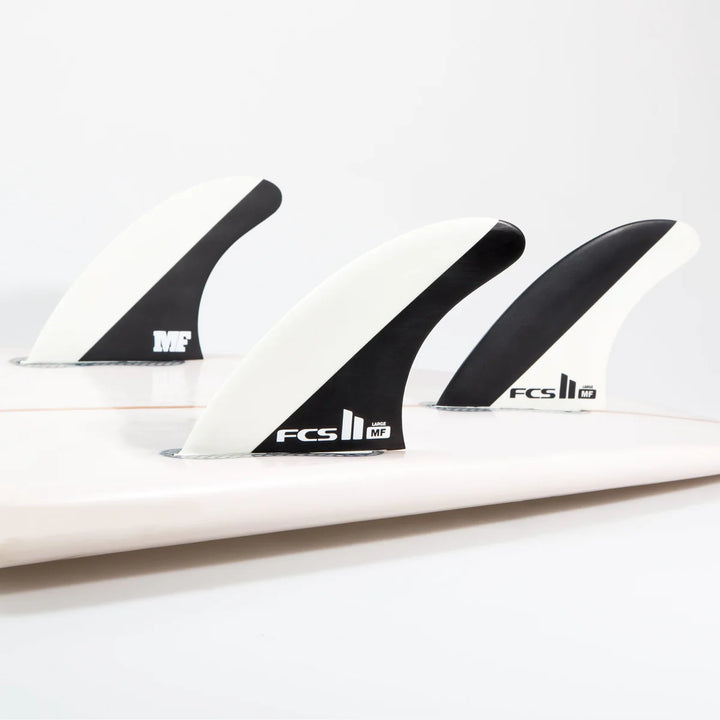 Three black and white surfboard fins with FCS logo on a white background
