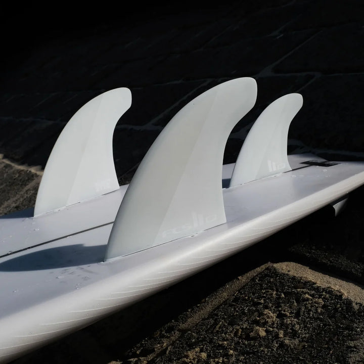 Close-up of a surfboard with three fins on a dark background