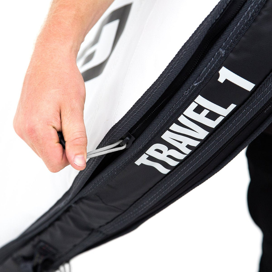 Close-up of person opening a black FCS surfboard bag with &