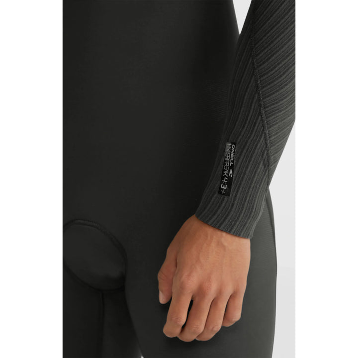 Close-up of a person wearing a black wetsuit with a brand label on the sleeve.