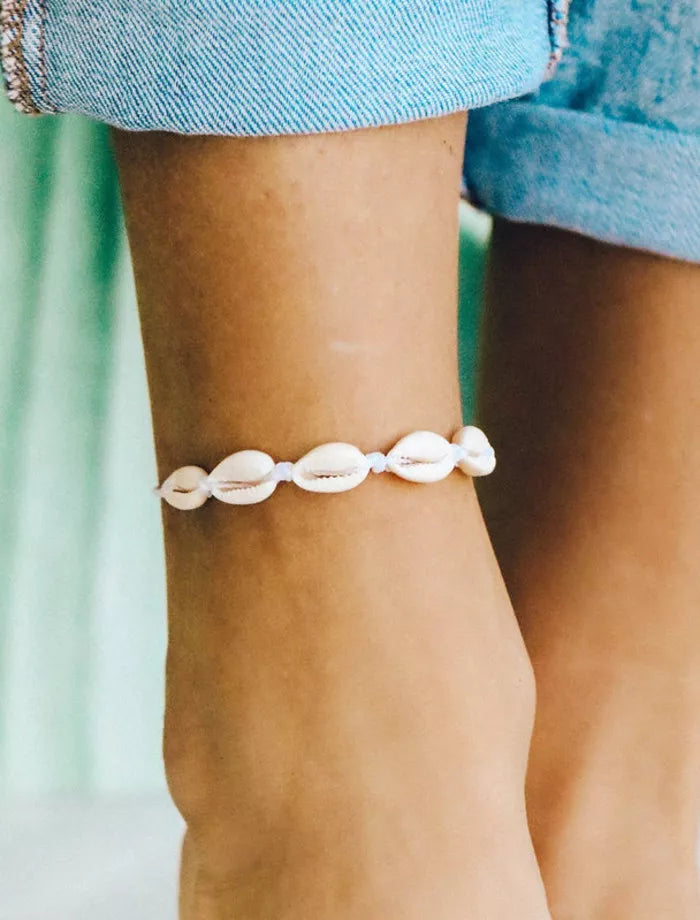 Shell anklet on a persons ankle with a blurred background