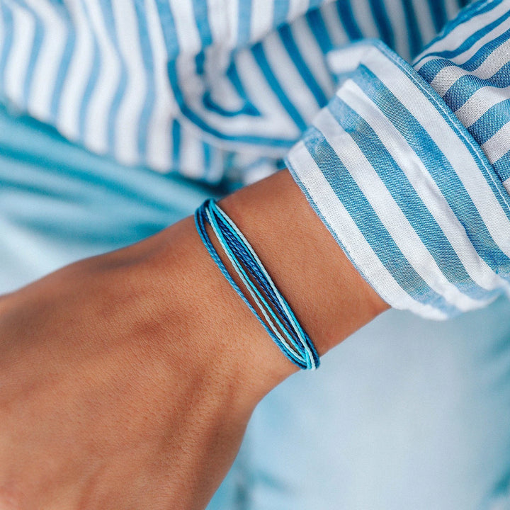 Close-up of a wrist with blue bracelets against a blurred background