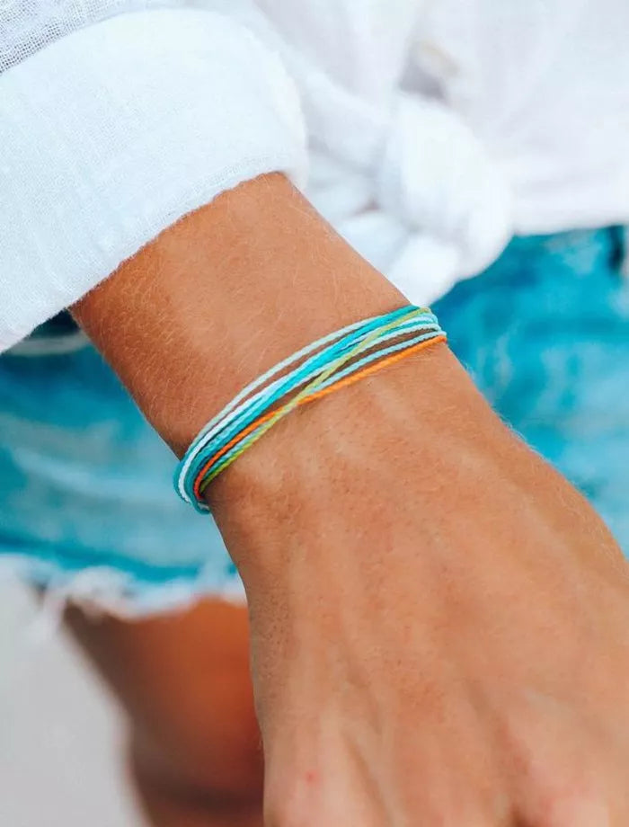 Close-up of a wrist wearing a colorful bracelet with a blurred denim background