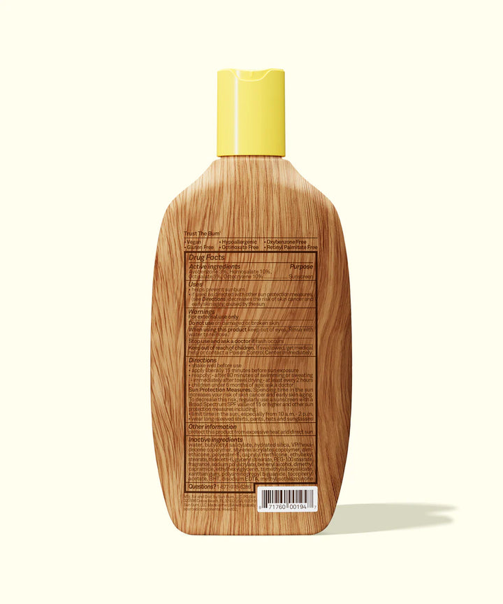 Rear of Sun Bum sun lotion bottle with ingredients on wood-effect packaging and yellow lid.