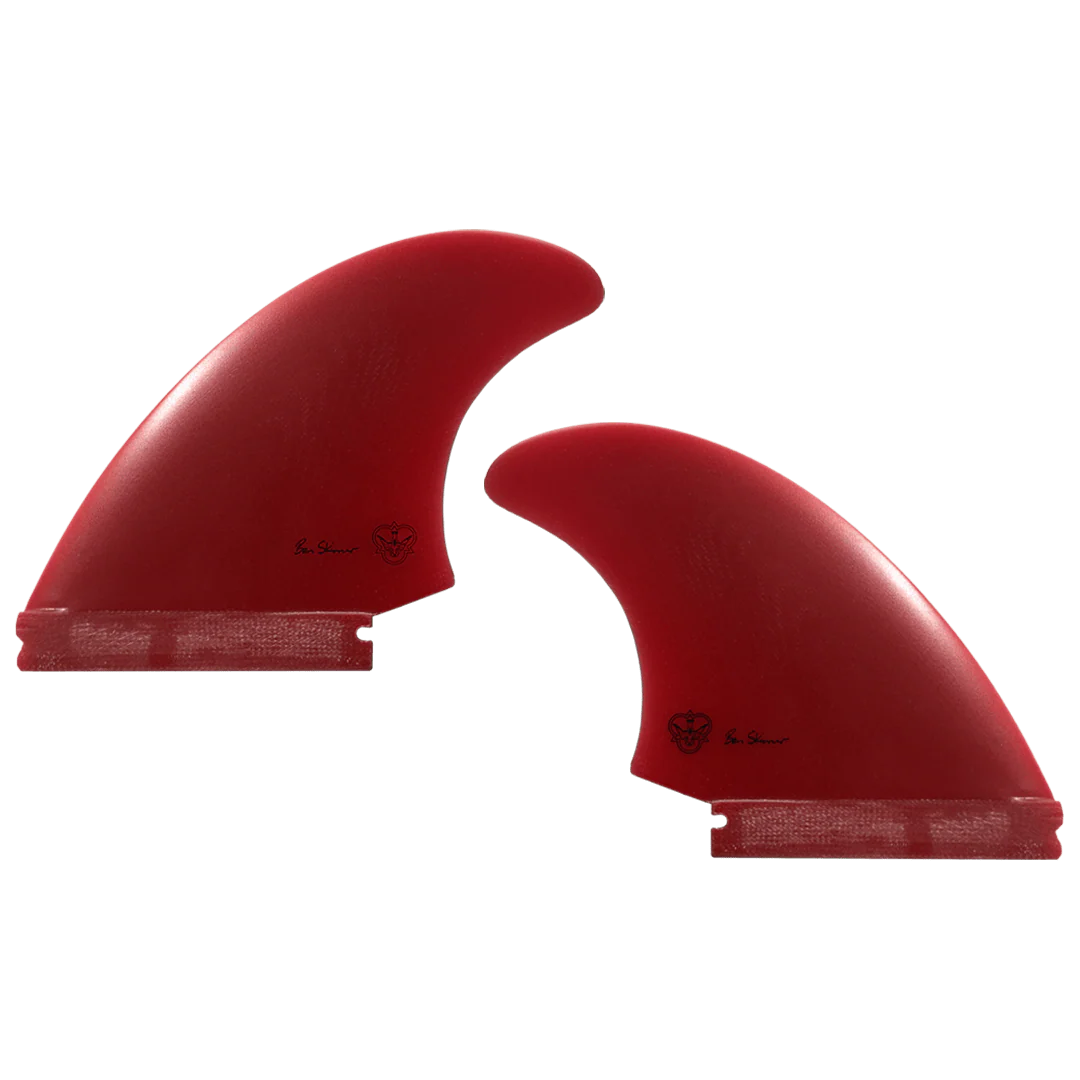 Two red surfboard fins, signed by Ben Skinner, on a white background