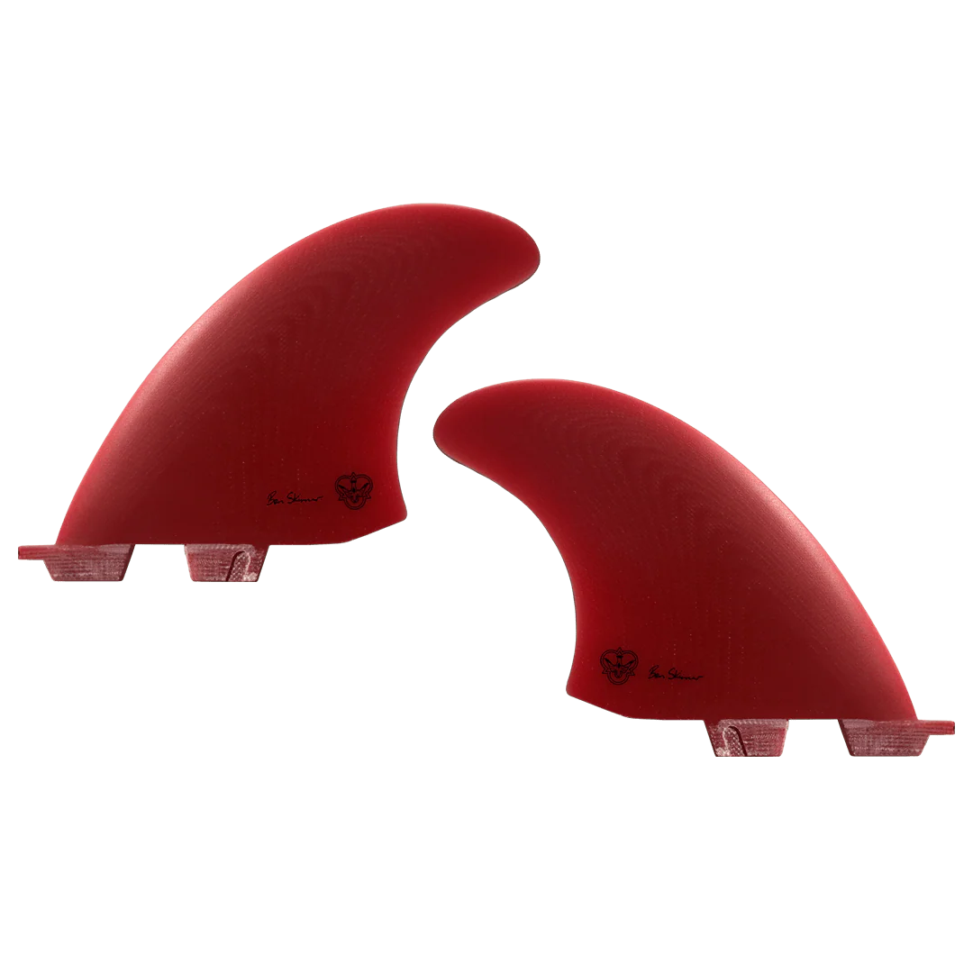 Two red surfboard fins, signed by Ben Skinner, on a white background