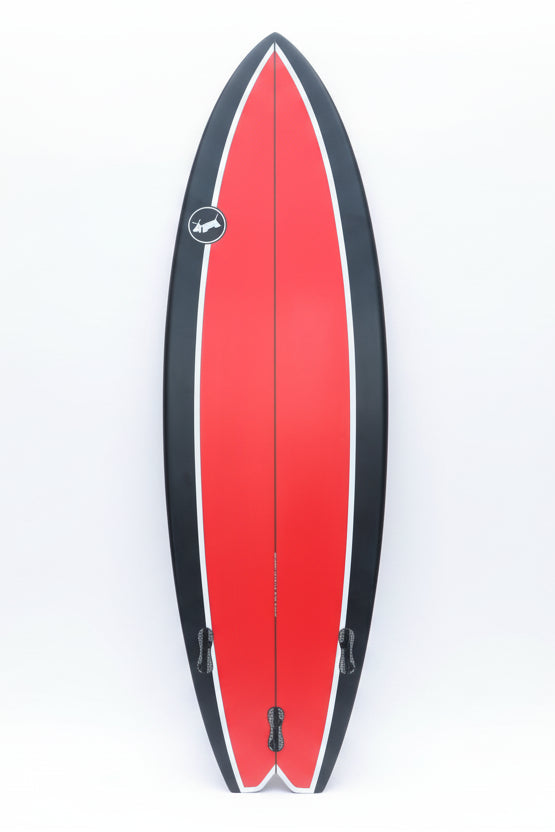 Red and black surfboard leaning against a white background.